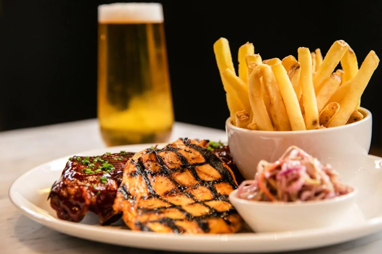 a plate with meat and French fries and a glass of beer at Sandman Signature Aberdeen Hotel & Spa in Aberdeen