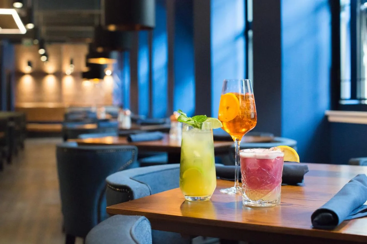 two drinks on a wooden table in a restaurant at Sandman Signature Aberdeen Hotel & Spa in Aberdeen